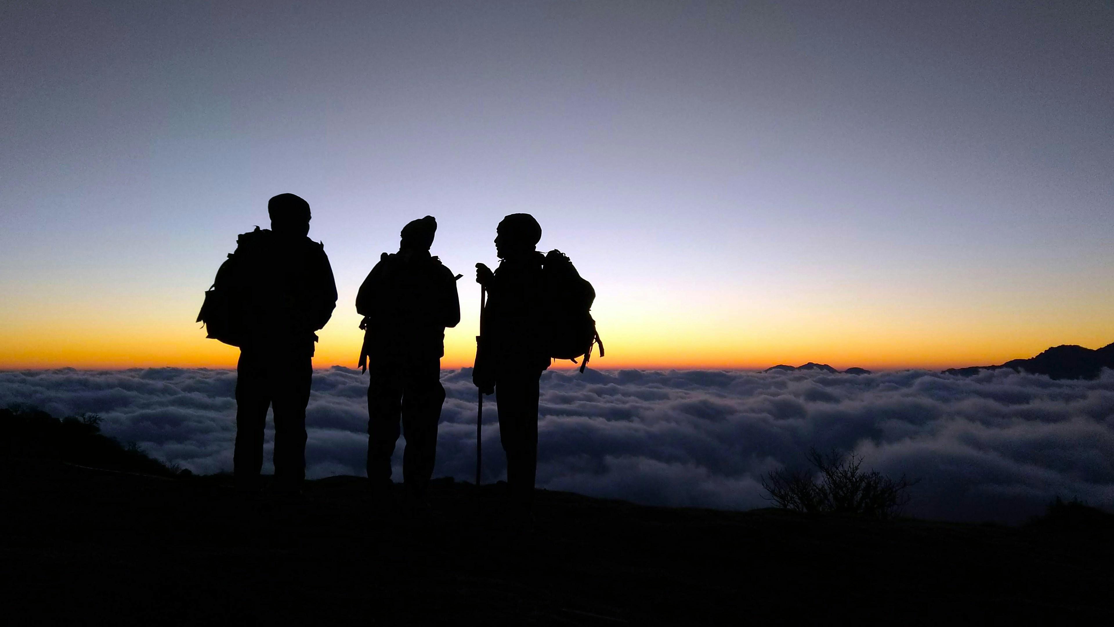 Image of hikers on mountaintop above clouds